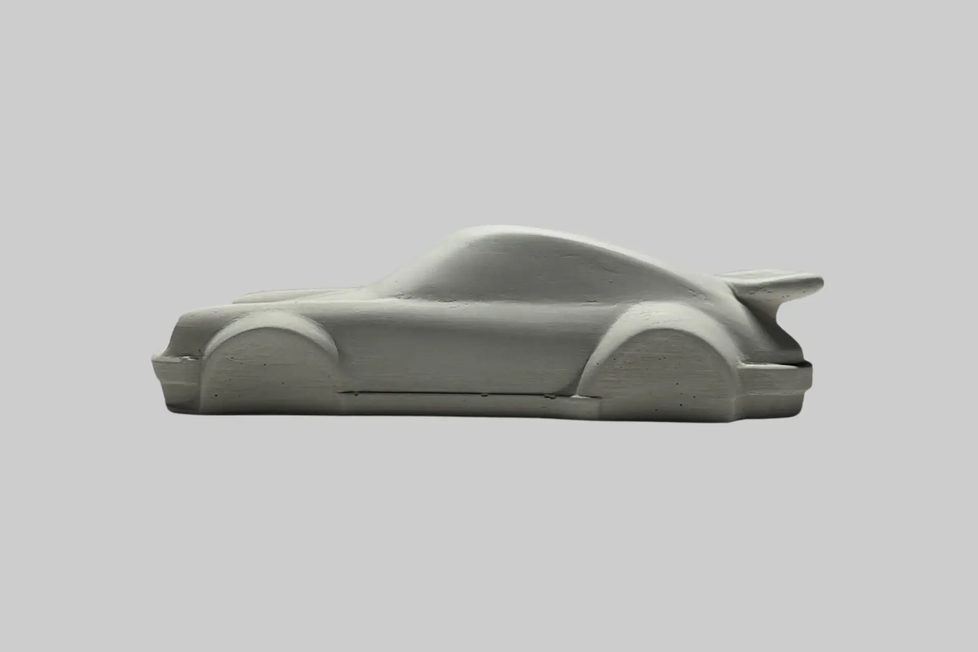 SPiedra Studios Porsche 911 Turbo concrete sculpture model on a desk, highlighting its minimalist design and detailing.