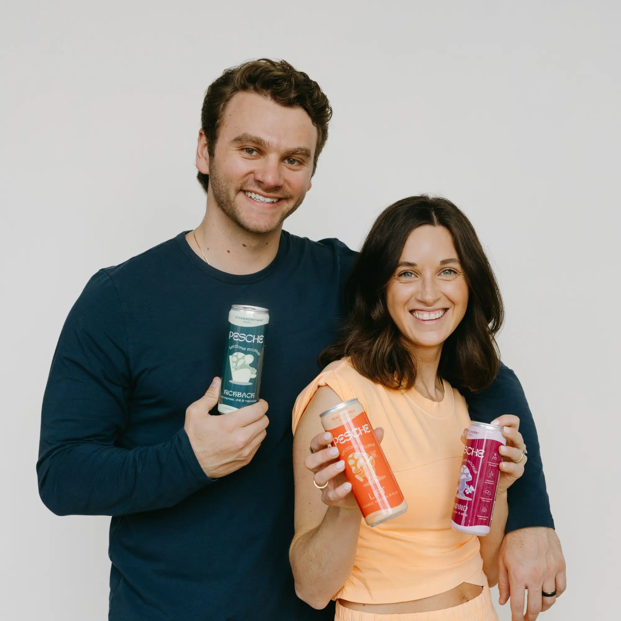 Pesche founders Taylor and Zack Grasso holding mocktail cans