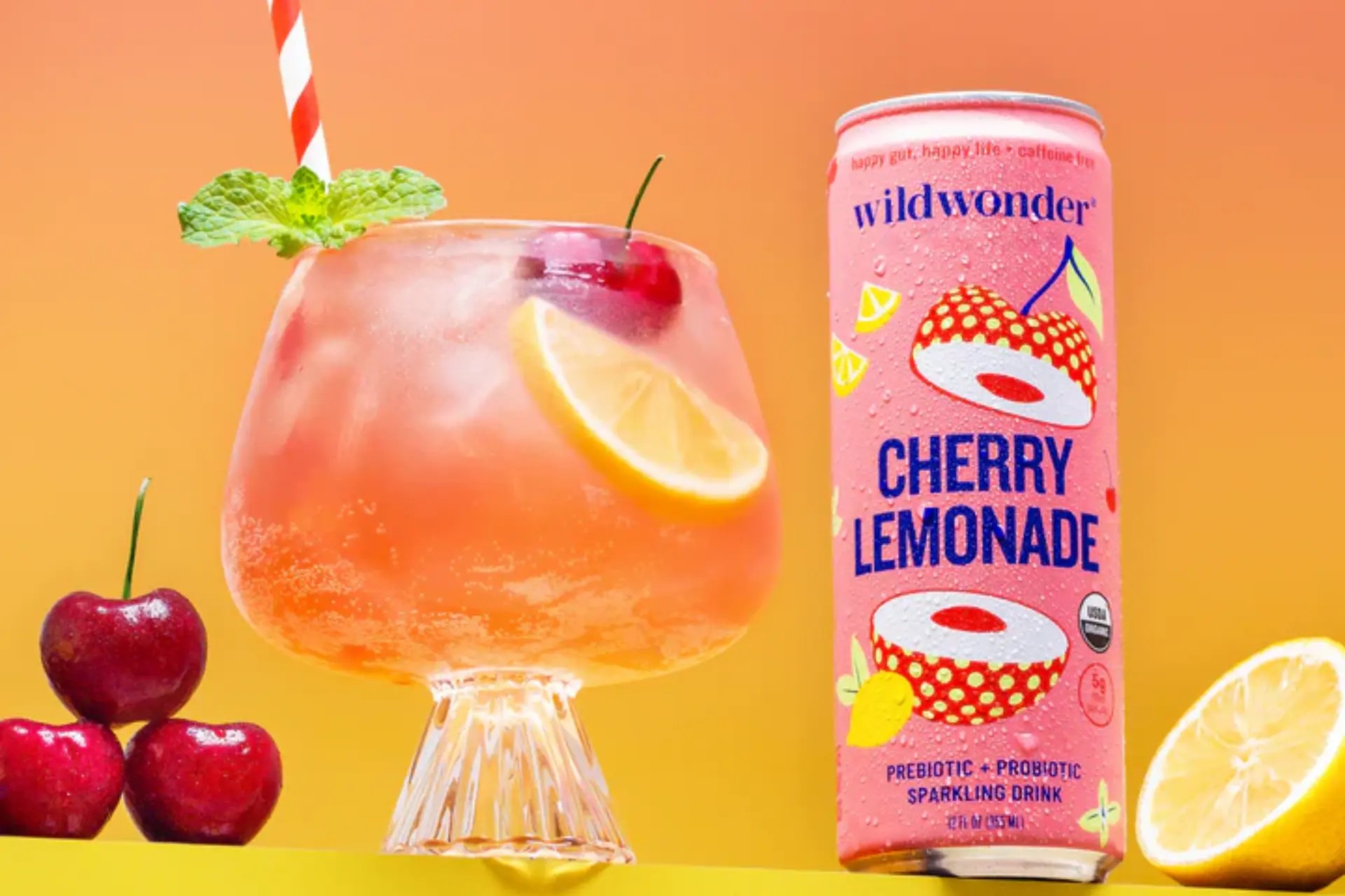 Wildwonder Cherry Lemonade can beside a glass with cherries and lemon slices